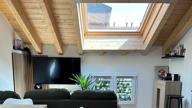A modern living space with a wooden ceiling, a black sofa, a TV, and a dining area with a table and chairs. - Bright Design Loft - Milan Certosa District (Milano)