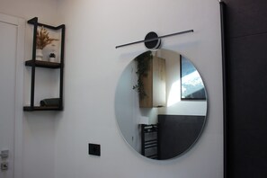 A room with a round mirror, a shelf with decorative items, and a door. - Bright Design Loft - Milan Certosa District (Milano)