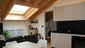 A modern kitchen with a skylight, a dining area with a table and chairs, a sofa, and a washing machine in the background. - Bright Design Loft - Milan Certosa District (Milano)