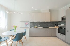 Une cuisine moderne avec des meubles gris, un plan de travail blanc et un four encastré.