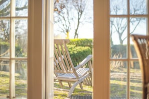 A wooden chair outside a window with a view of a garden. - Charming cottage in Umbria with private pool (Umbria)