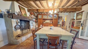 A rustic dining area with a stone fireplace, wooden beams, and a chandelier.