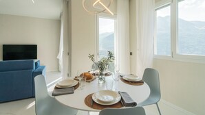 Un coin repas avec une table ronde, des chaises, des assiettes, des verres et une plante.