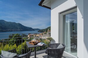 Un balcon avec une table, des chaises et une vue sur un lac et des montagnes.