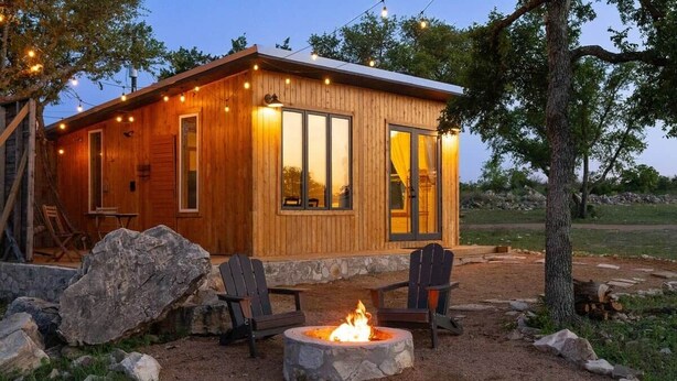 A wooden cabin with a fire pit and Adirondack chairs. - Cedar Haus - king bed and soaking tub (Marble Falls)