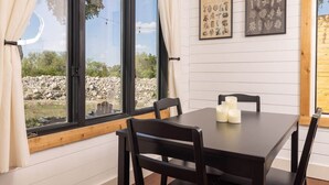 A dining area with a table, chairs, and candles. There are two framed botanical prints on the wall. - Cedar Haus - king bed and soaking tub (Marble Falls)