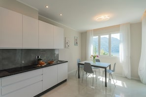Una cucina moderna con mobili bianchi, un piano di lavoro nero e un'area pranzo con tavolo e sedie.