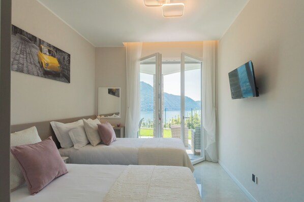 Habitación de hotel con dos camas, un televisor, un cuadro y vistas a montañas a través de un ventanal.