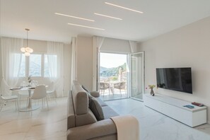 Un soggiorno moderno con divano, tavolo da pranzo, sedie, televisore e un balcone con vista.