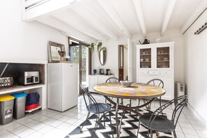 Una cocina con una mesa redonda, sillas, un refrigerador, armarios y un microondas.