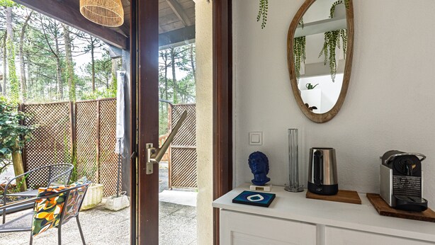 Una habitación con un armario blanco, un espejo con marco de madera y una cafetera.