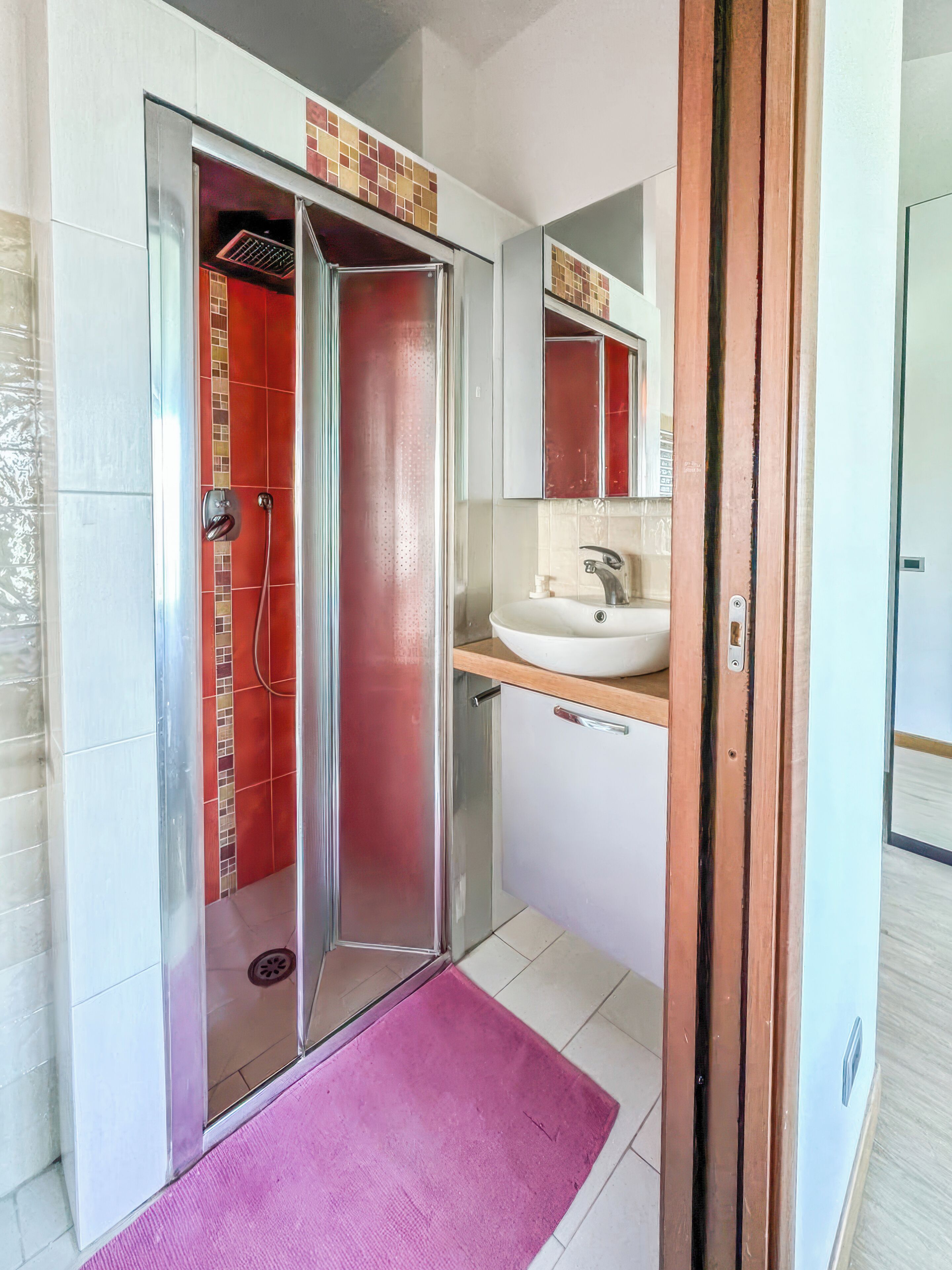 A bathroom with a shower, sink, and mirror.