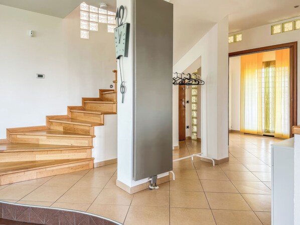 A staircase leading to a second floor, a modern kitchen area, and a view of the outside through a glass door. - Villarzilla (Rome)