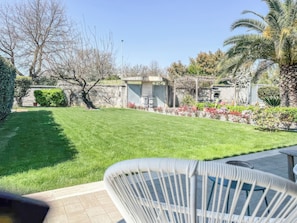 A well-maintained lawn, a patio area with a chair, and a small building with a door. - Villarzilla (Rome)