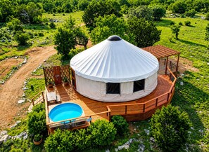 Una yurta con terraza de madera y piscina.