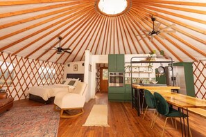 A yurt interior with a bed, kitchenette, and seating area.