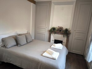 Una camera da letto con un letto, cuscini, un camino e uno specchio.