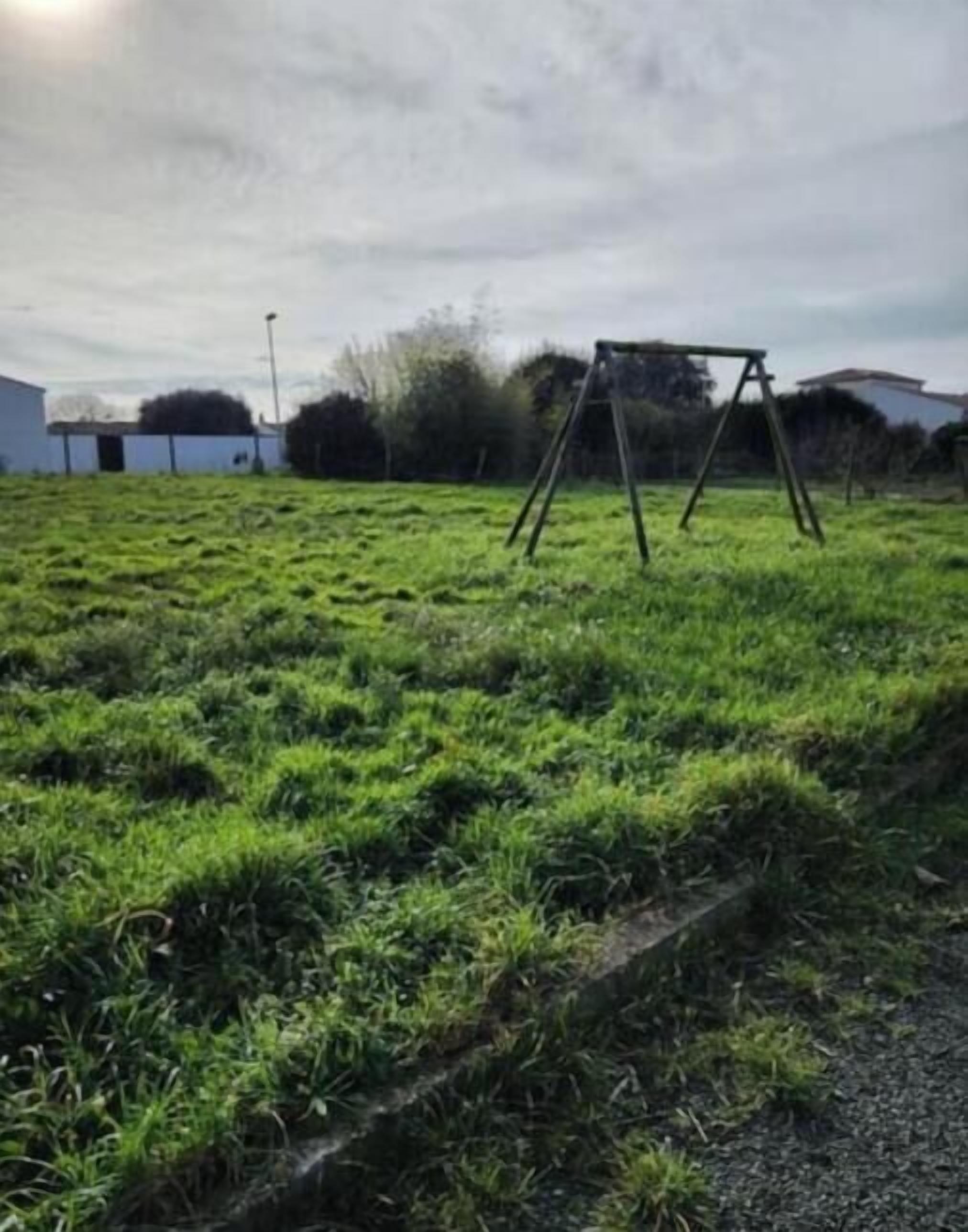Ein grünes Feld mit einer Schaukel und einem Gebäude im Hintergrund.