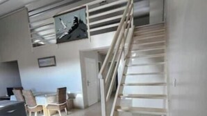 Een trap naar een verdieping, een bureau met stoelen en een lijst aan de muur.