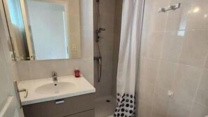 Een badkamer met een wastafel, spiegel, douche, toilet en een douchegordijn met stippen.