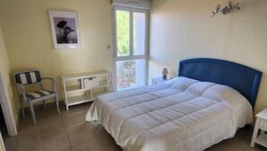 Een slaapkamer met een bed, een stoel, een raam en een deur.