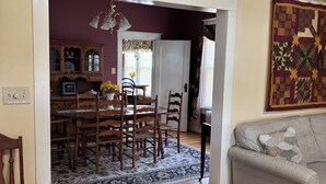 A dining area with a wooden table and chairs, a patterned rug, and a gray sofa. - Spacious 5-bedroom house in serene Fincastle with AC (Fincastle)