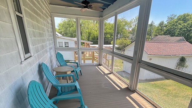 A covered porch with blue Adirondack chairs, a ceiling fan, and a view of neighboring houses. - Spacious 5-bedroom house in serene Fincastle with AC (Fincastle)