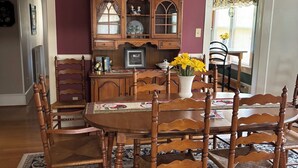 A dining room with a wooden table, chairs, a chandelier, and a patterned rug. - Spacious 5-bedroom house in serene Fincastle with AC (Fincastle)