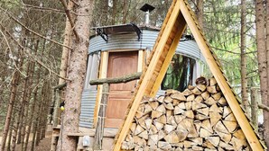 A cabin with a triangular roof, a wooden door, and a stack of firewood. - Bin There Treehouse - A Grain Bin treehouse! (Washington County)