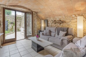 Un salon chaleureux avec un mur en pierre, un canapé, une table basse et une porte-fenêtre coulissante donnant sur un espace extérieur.