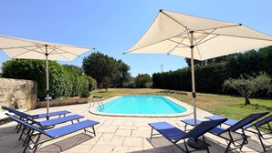 Una piscina rettangolare con bordo piastrellato, circondata da lettini e ombrelloni.