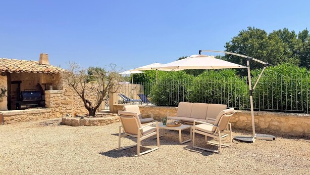Un'area salotto esterna con tavolo e sedie, un barbecue e un pergolato con tettoia.