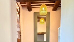 Una scala con finitura in legno che conduce a una stanza con uno specchio e un lampadario.