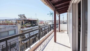 A balcony with a metal railing overlooking a cityscape, a building with scaffolding, and a clear sky. - Peristeri 1 Bd Apt w Balcony and View (Peristeri)