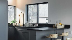A modern kitchen with a large island, dark cabinetry, and a wooden ceiling.