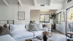 A modern living room with a sofa, coffee table, and a dining area with chairs and a table.