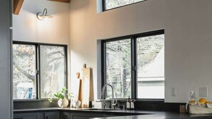 A modern kitchen with dark cabinetry, a large island, and a dining area with a table and chairs.