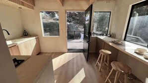 Une cuisine moderne avec un plancher en bois, de grandes fenêtres et une vue sur l’extérieur.