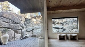 Une pièce dotée d’une grande fenêtre, d’un plancher en bois et offrant une vue sur un paysage rocheux.