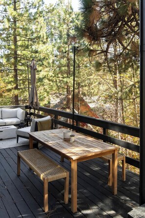 A wooden deck with a table and benches, surrounded by trees. - Elmwood Lake House, by @halfway_wholeistic (Lake Arrowhead)