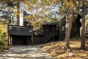 Ein Gebäude mit überdachter Eingangspartie, einer Treppe und einem Baum im Vordergrund.