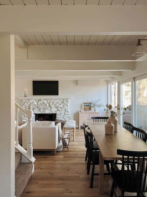 Un interior moderno con comedor, chimenea y televisor montado en la pared.