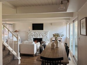 Amplia sala de estar con chimenea, una mesa de comedor y una escalera.
