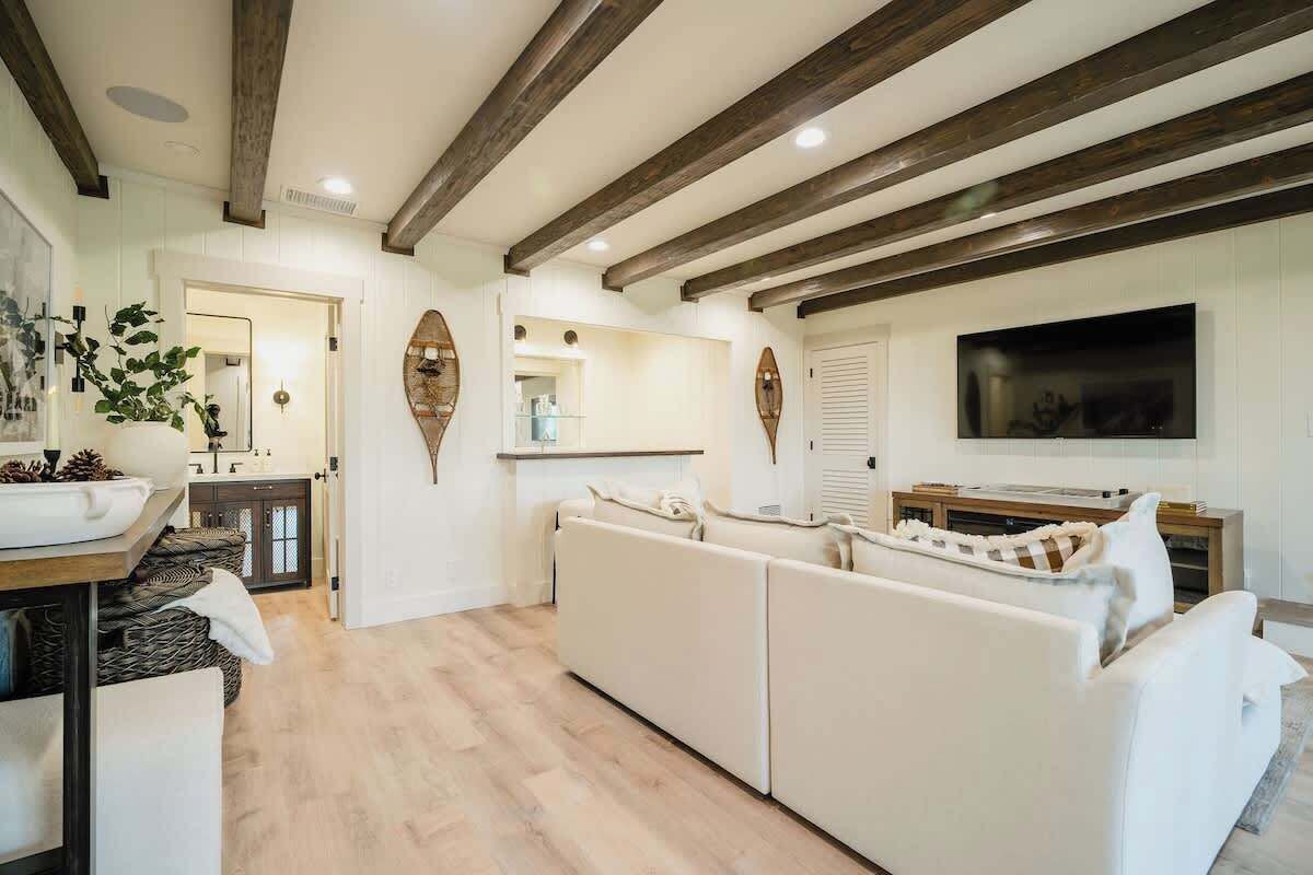 Una sala de estar moderna con un sofá, un televisor y una cocina al fondo.
