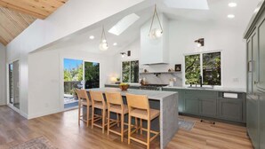 Una cocina moderna con una isla central, sillas de madera y vistas al exterior.