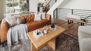 Un salón moderno con techo de madera, una escalera y vistas al exterior.