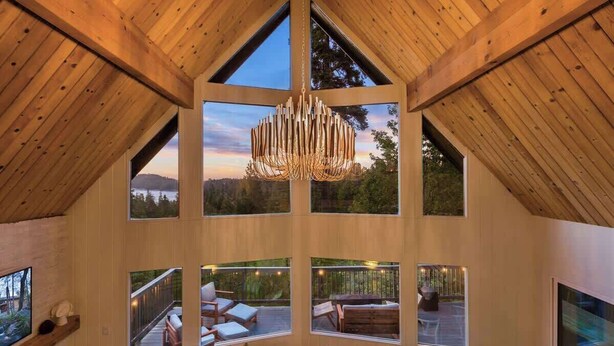 Una habitación con techos altos, ventanas amplias, un colgante de luz y un balcón con mobiliario exterior.