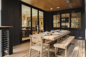 An indoor dining area with a wooden table set for four, benches, and a large window. - Ravenwood House, lakefront on Orchard Bay (Lake Arrowhead)