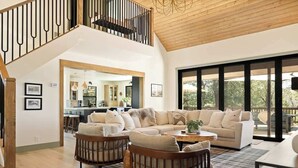 A spacious living area with a large sectional sofa, two armchairs, a coffee table, and a dining table. A staircase with a wooden railing leads to an upper level. - Geneva Pines (walk to lake!) (Lake Arrowhead)