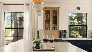 A kitchen with a marble countertop, a wooden cabinet, and a window with a view of trees. - Geneva Pines (walk to lake!) (Lake Arrowhead)